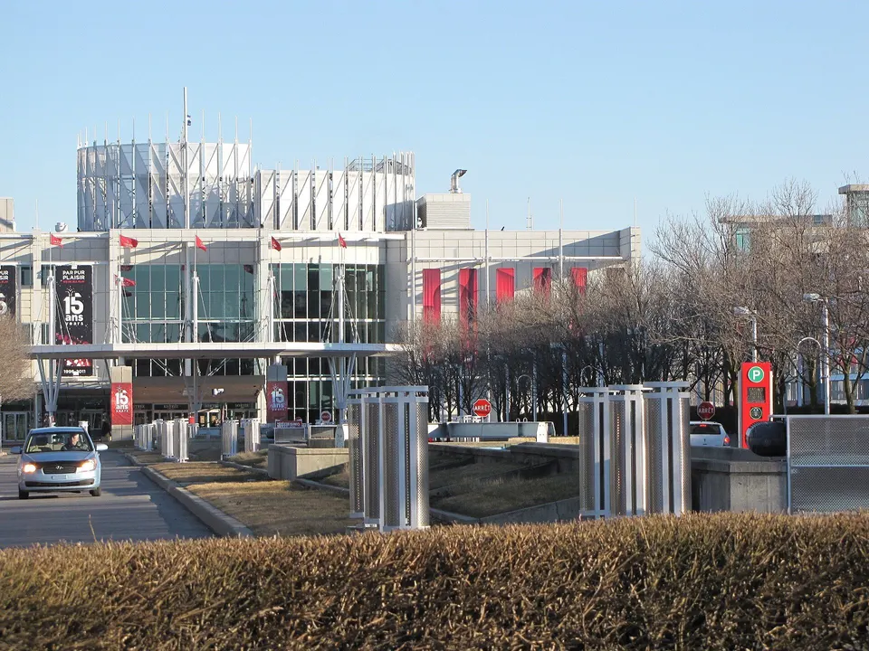 Façade vitrée du Casino du Lac-Leamy, entrée principale, avec des bannières rouges et des drapeaux, par une journée claire.